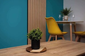 A wooden table with a potted plant, yellow chairs, and a wooden partition in a modern interior. - Bondi beach Getaway - One bedroom apartment (Tyne and Wear)