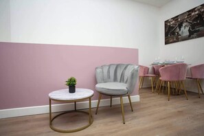 A modern room with a round table, a grey armchair, and a pink wall. - Monte Carlo Inspired Two Bedroom duplex apartment (Tyne and Wear)