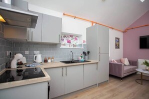 A compact kitchen with a built-in stove, a sink, and a window with a floral design. - Monte Carlo Inspired Two Bedroom duplex apartment (Tyne and Wear)