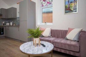 A modern kitchen with grey cabinets, a marble table, and a pink sofa with cushions. - Monte Carlo Inspired Two Bedroom duplex apartment (Tyne and Wear)