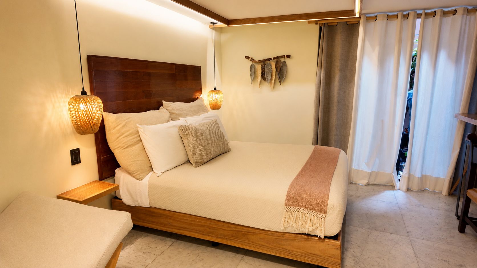 A modern bedroom with a wooden headboard, a bed with multiple pillows, a bedside table, and a hanging light fixture.