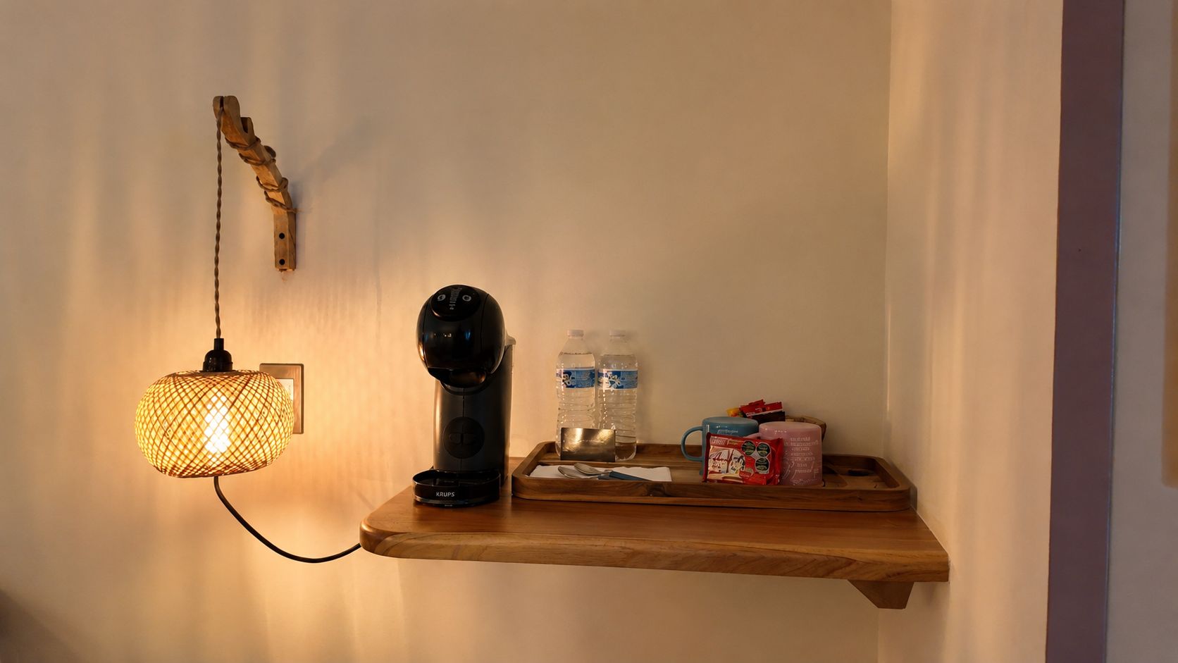 A wall-mounted shelf with a coffee maker, a water bottle, and a tray with snacks.