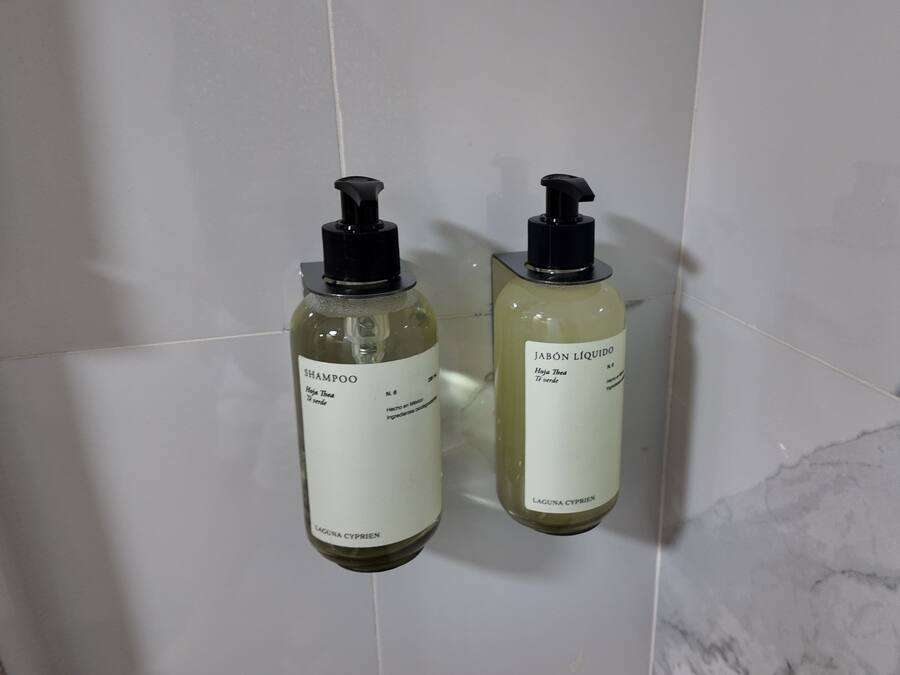 Two bottles of shampoo on a tiled wall.