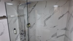 A glass-enclosed shower with marble walls and a handheld showerhead. - Terraza & Loft San Ángel (Mexico City)
