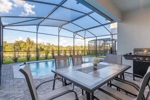 Relax and dine al fresco in this serene outdoor space, featuring a pool, dining table, and grill.