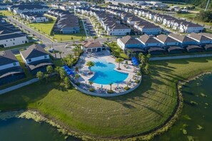 Residential area with a central pool surrounded by houses with pitched roofs and manicured lawns.