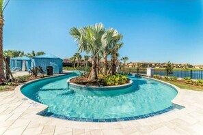 Relax by the pool surrounded by lush greenery and palm trees.