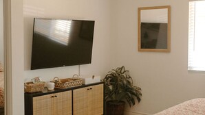 A bedroom with a bed, a television, a ceiling fan, a potted plant, and a mirror. - Walk to Beach! - Cozy SC Studio (San Clemente)