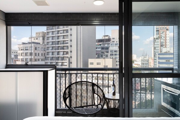 A modern room with a large window, a black chair, and a small table with a bottle.