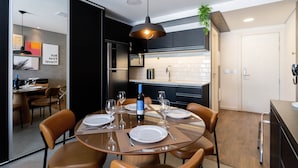 Un comedor moderno con una mesa redonda para cuatro personas, una botella de vino y una lámpara colgante.