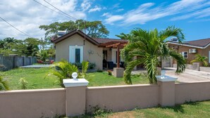 A residential house with a front yard, a patio, and a small garden area. - Trove Manor (St. Ann's Bay)