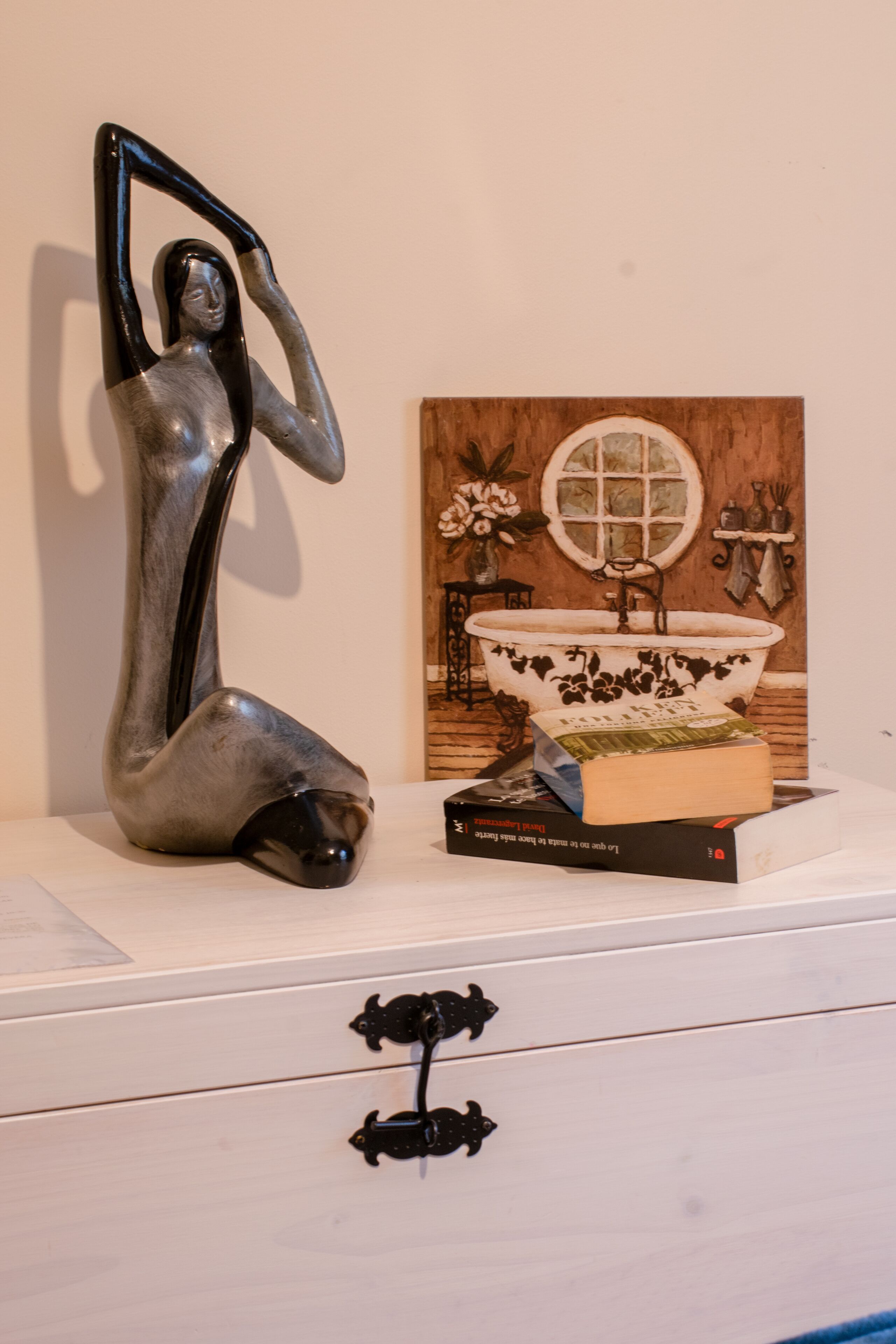 A sculpture, a vintage-style sink, and a book on a dresser.