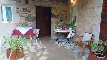 A stone-walled patio with a table and chairs, surrounded by potted plants.