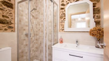 A bathroom with a glass-enclosed shower, a white sink, and a mirror above it.