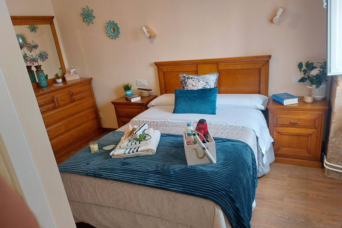 A neatly arranged bedroom with a bed, wooden nightstands, a dresser, and decorative wall art.