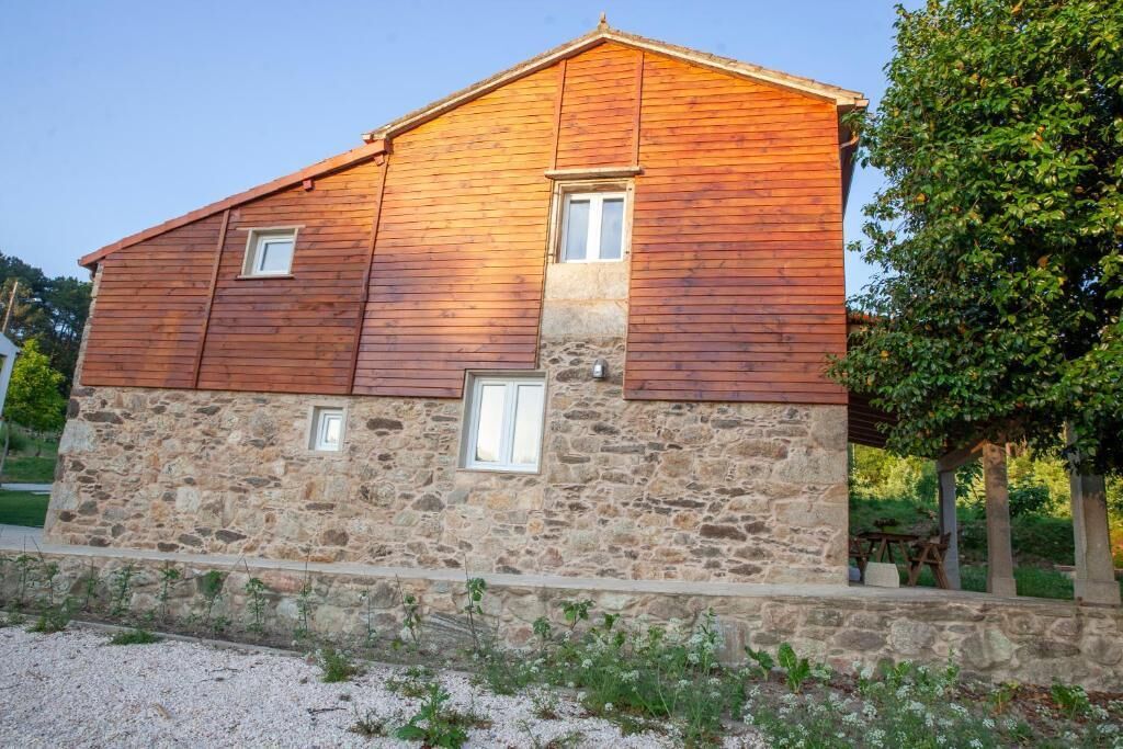 Un edificio de piedra de dos pisos con revestimiento de madera, una ventana pequeña en el piso superior y un cimiento de piedra.