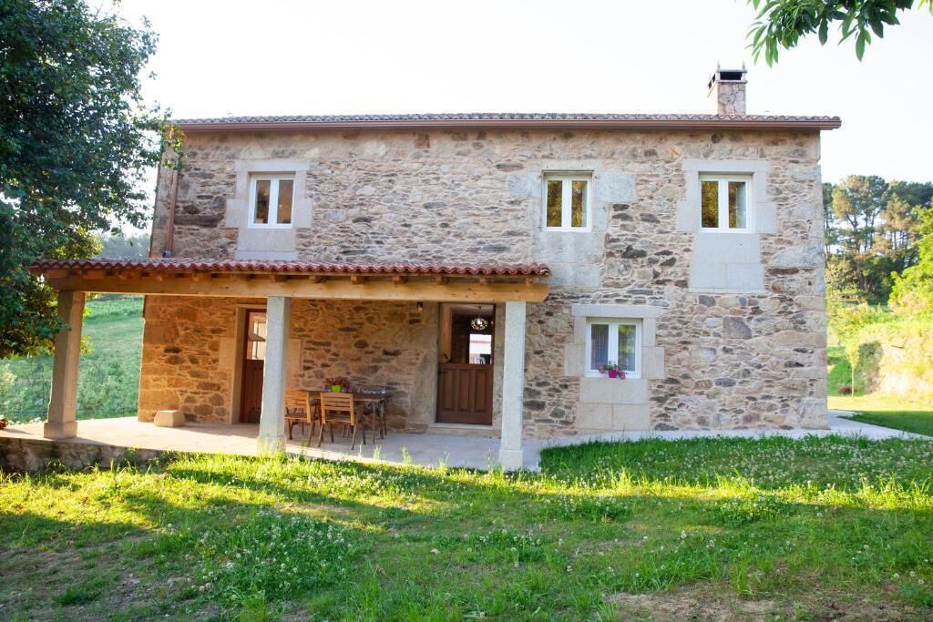 A stone house with a covered patio, a door, and a window.