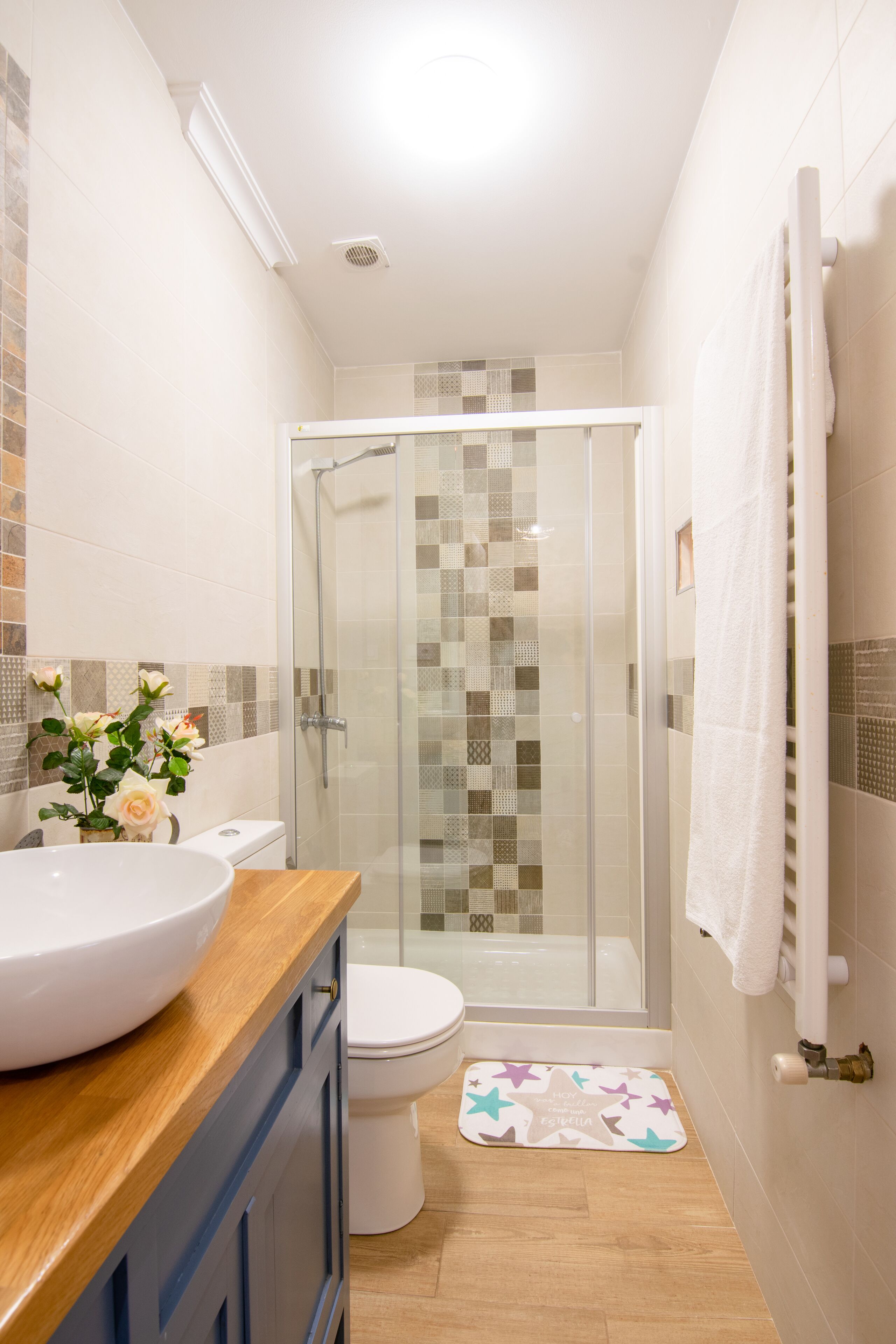 A bathroom with a glass-enclosed shower, a white sink, and a toilet.