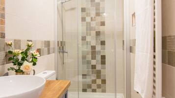 A bathroom with a glass-enclosed shower, a white sink, and a toilet.