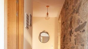 Un pasillo con suelo de madera, pared de piedra y puerta de madera.