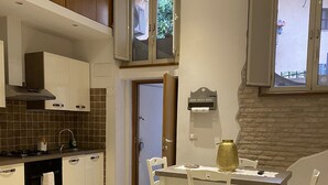 Une cuisine moderne avec un coin repas, comprenant un canapé en cuir noir, une table à manger avec des chaises et un mur en pierre.