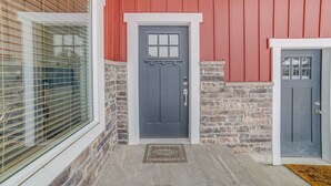 A house with a red exterior, a gray front door, and a window with blinds.