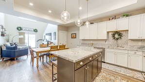 A spacious kitchen with a large island, white cabinetry, and pendant lighting.