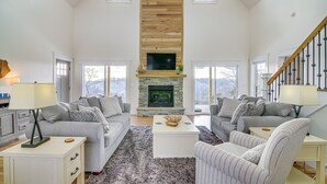 Un salón amplio con chimenea, dos sofás, una mesa de centro y una escalera.