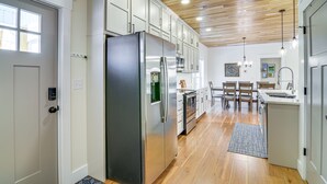 Una cocina moderna con armarios blancos, electrodomésticos de acero inoxidable y techo de madera.