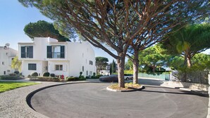 Una moderna casa a due piani con vialetto, un albero e un'auto parcheggiata.