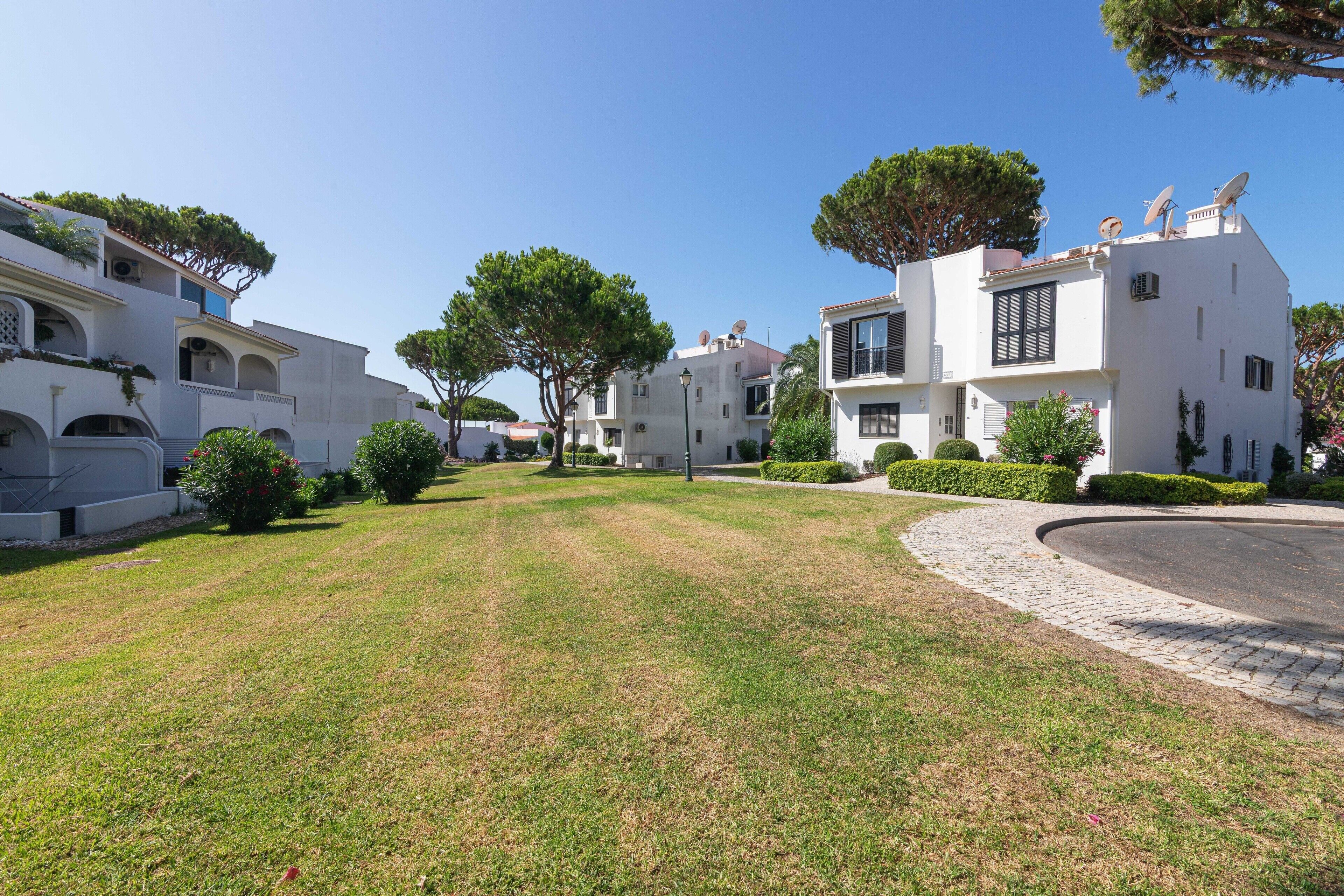 Un quartiere residenziale con edifici bianchi, un prato curato e un vialetto curvo.