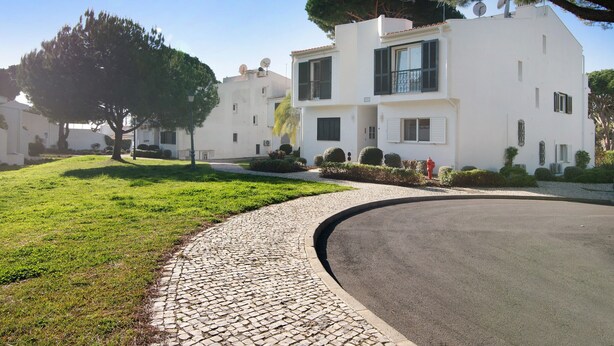Un edificio moderno su due piani con vialetto lastricato, immerso nel verde di prati curati e alberi.