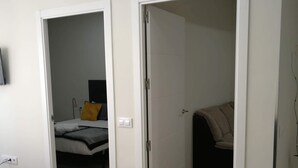 Une pièce comprenant un lit, un bureau et deux portes ouvertes donnant sur d’autres pièces.