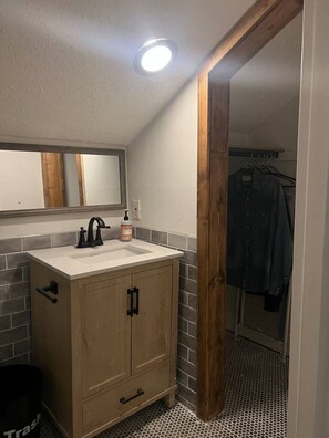 Un bagno con un mobile lavabo in legno, uno specchio e uno schienale piastrellato.