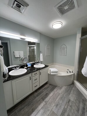 Un baño moderno con dos lavamanos, una bañera grande y una ducha a pie.