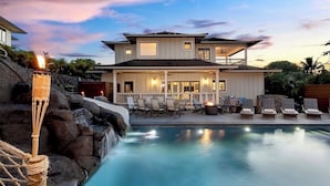 Ein zweistöckiges Haus mit Pool, Sitzgelegenheiten im Freien und einem Wasserfall.
