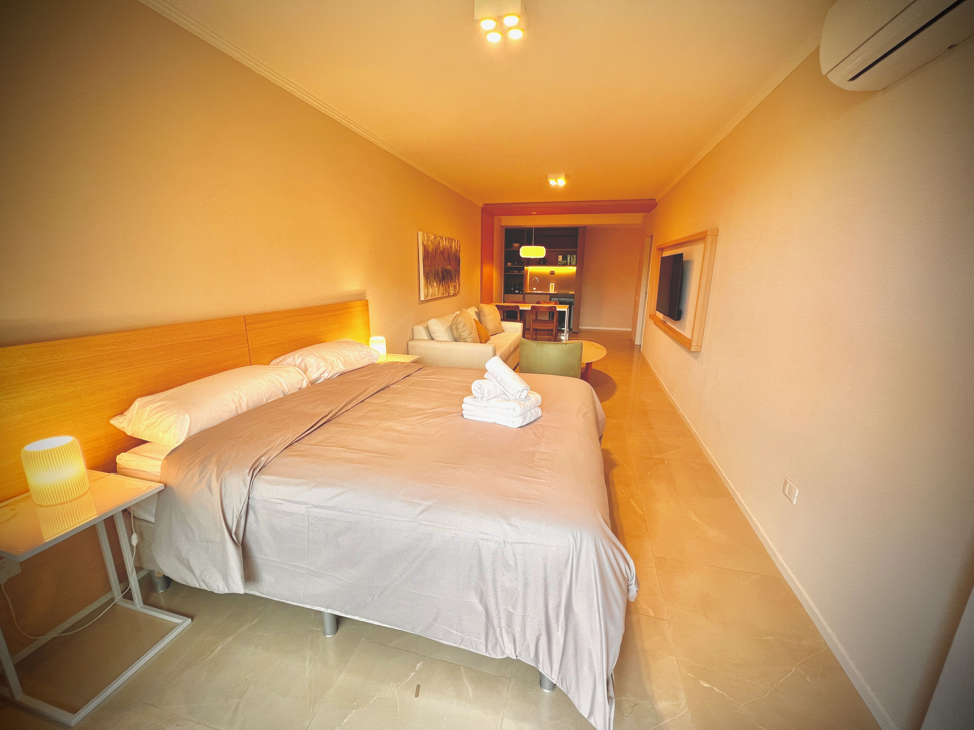 A hotel room with a large bed, bedside tables, a desk, and a chair.