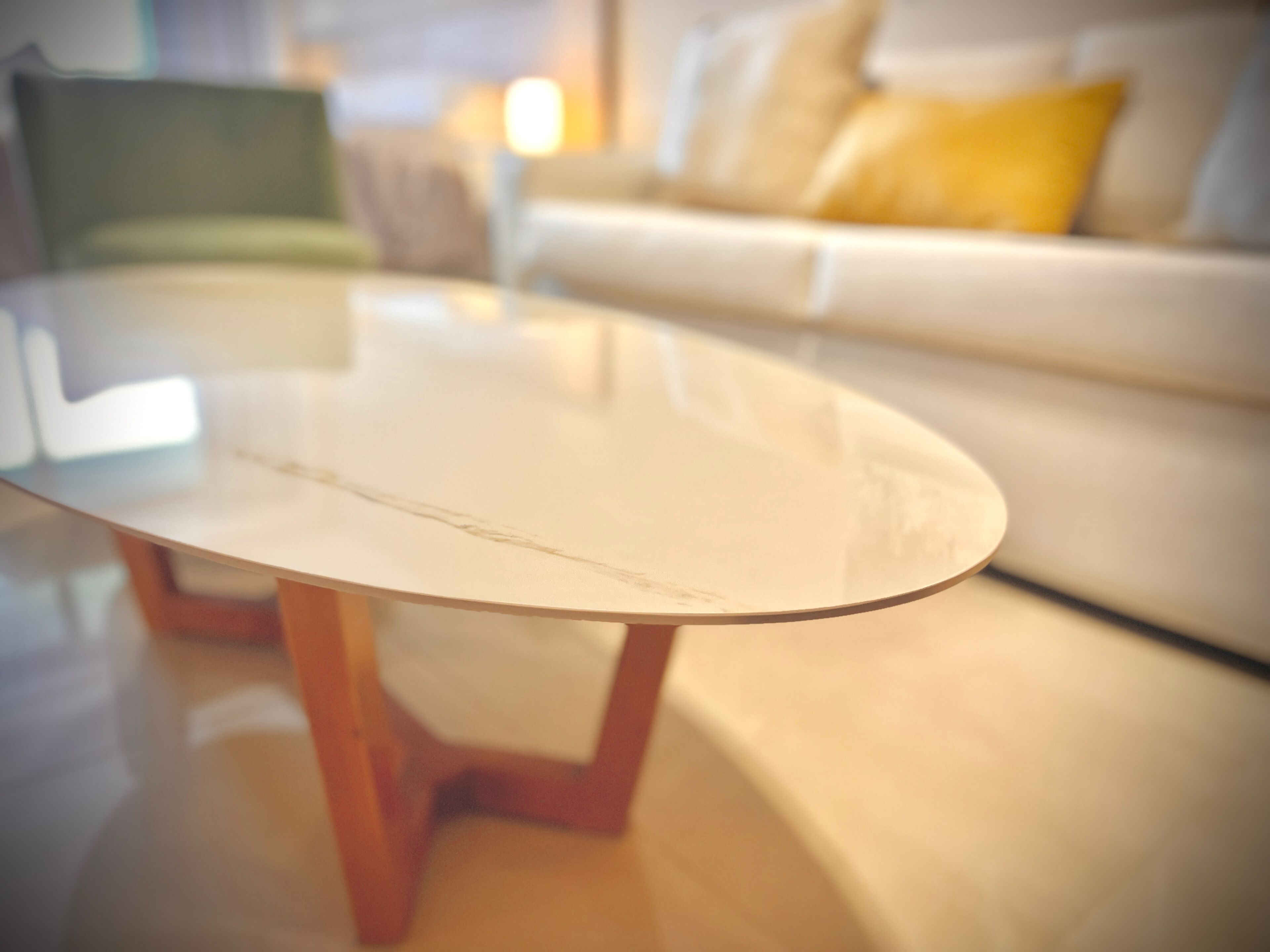 Una mesa de centro redonda de vidrio con patas de madera en una sala de estar.