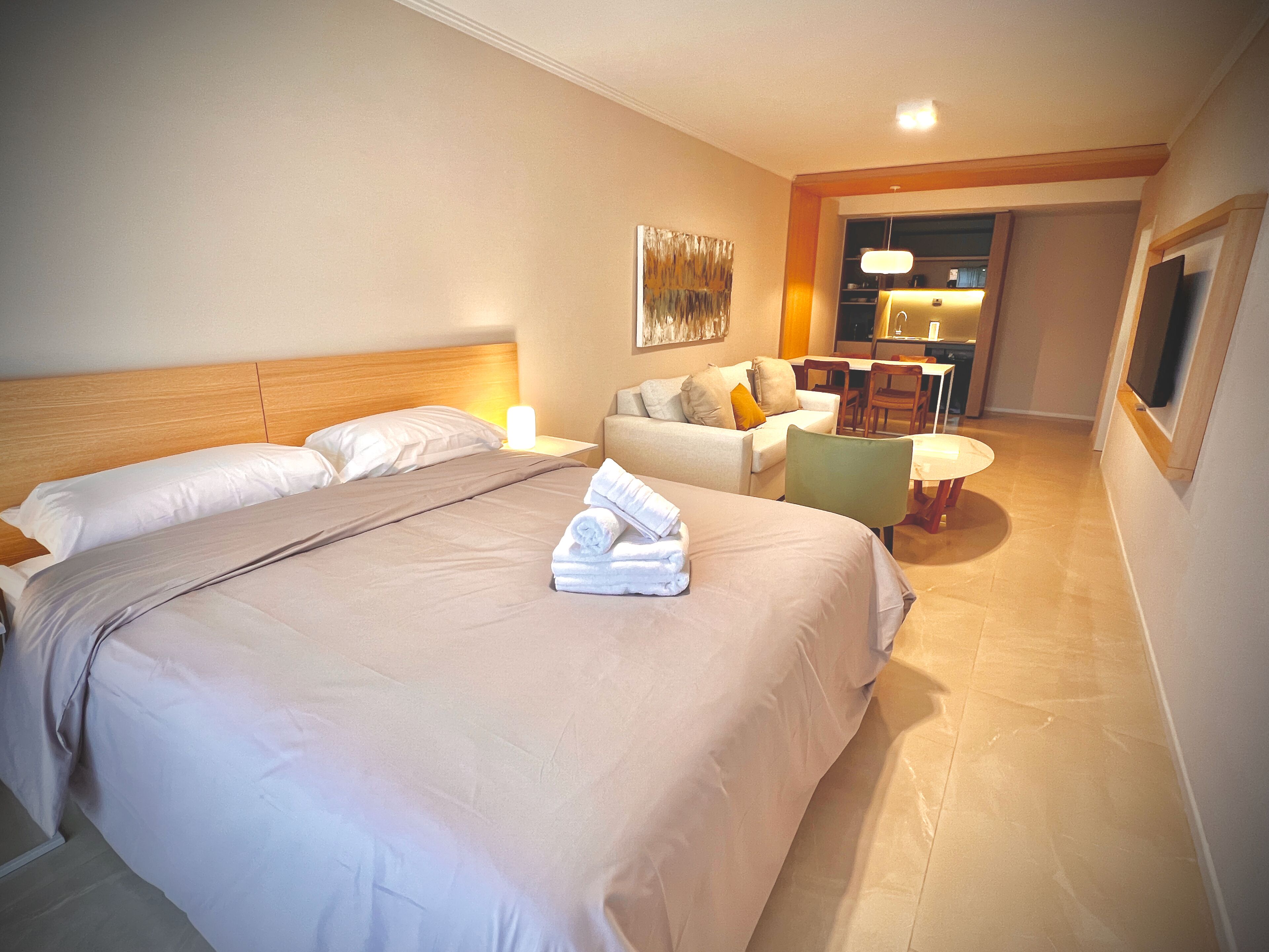 A hotel room with a large bed, a sofa, a small table, and a TV.