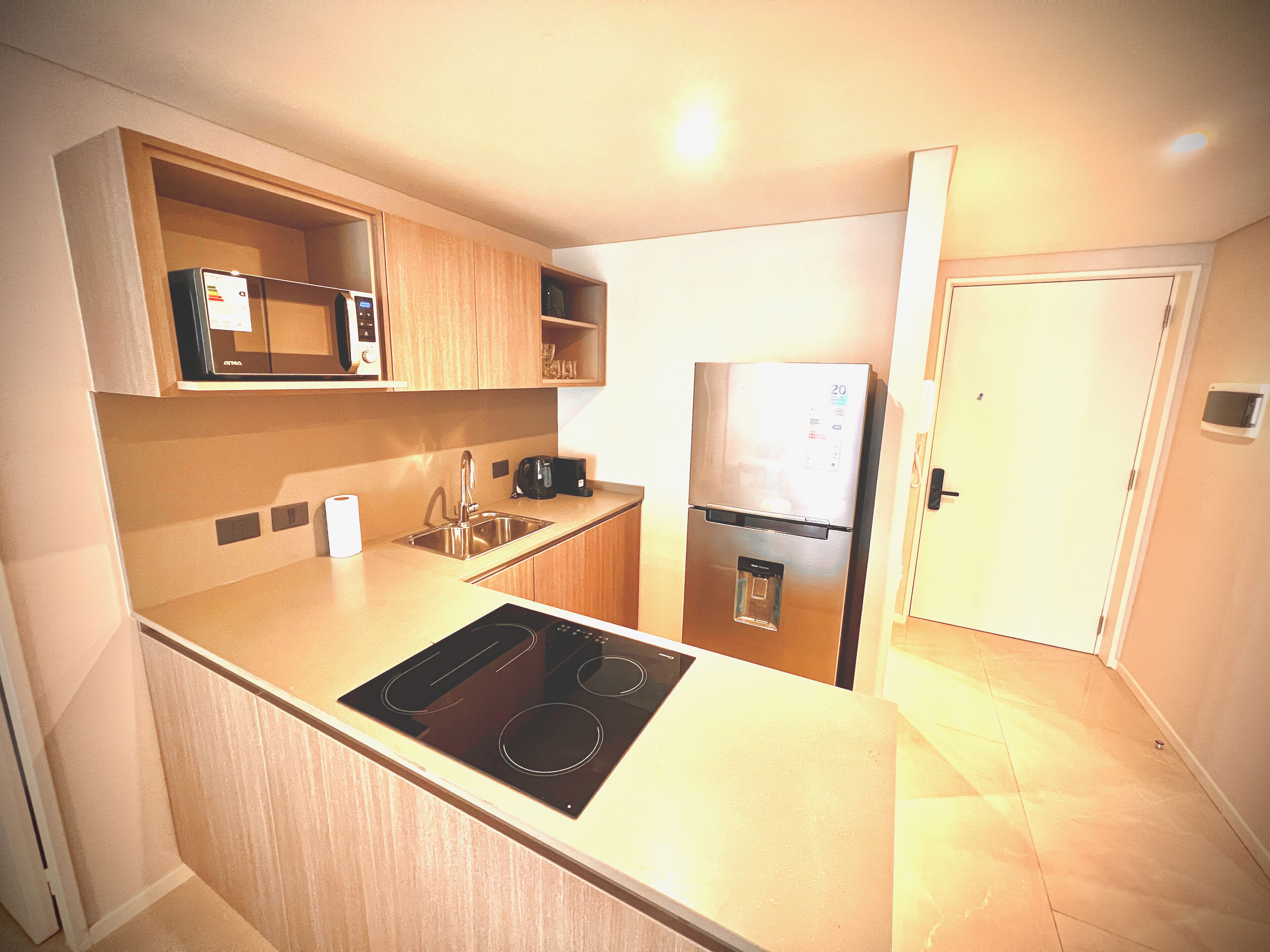 A compact kitchen with a microwave, stove, sink, and refrigerator.
