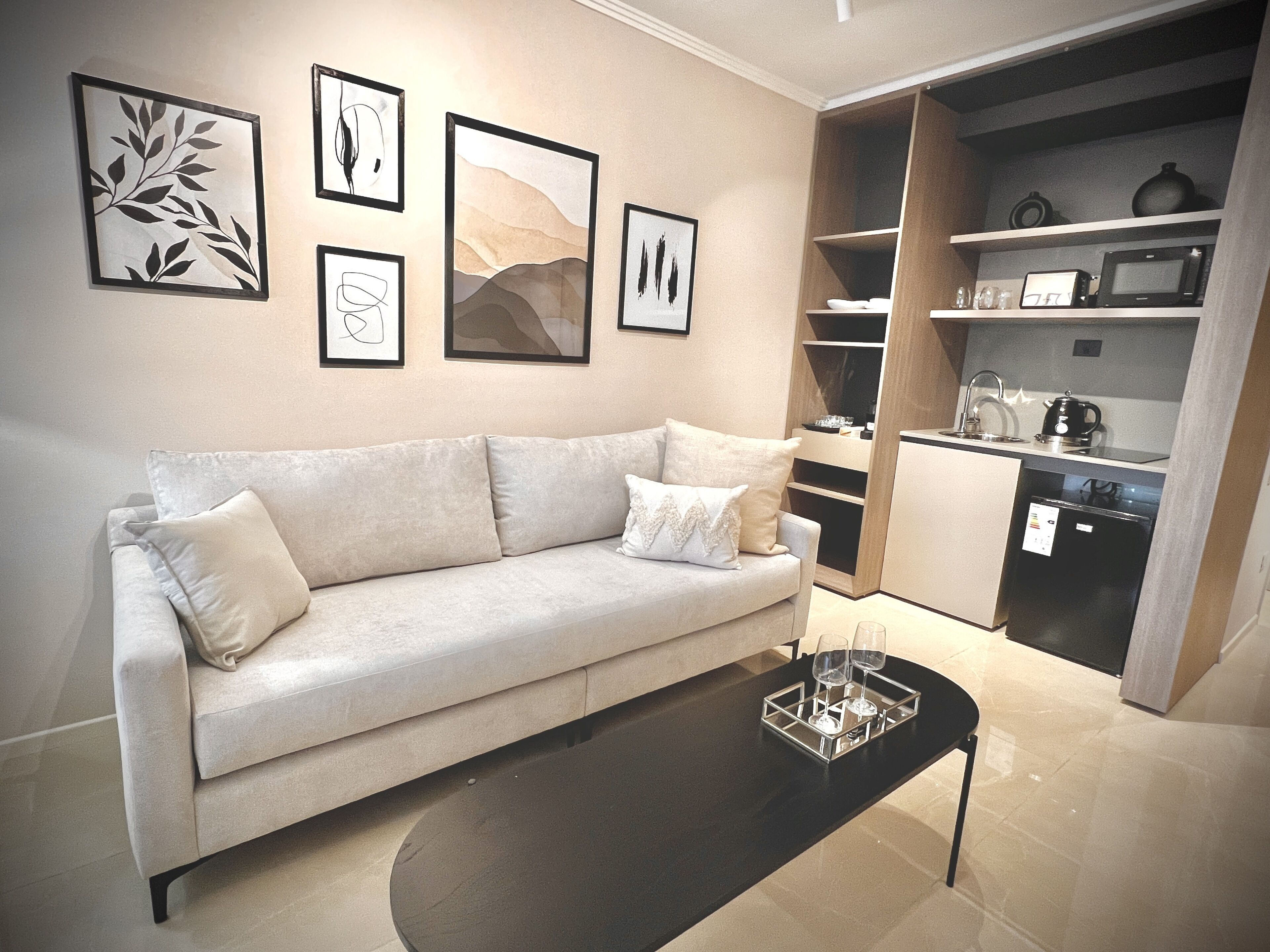 Ein modernes Wohnzimmer mit einer Couch, einem Couchtisch und einer Küchenzeile mit Geräten.
