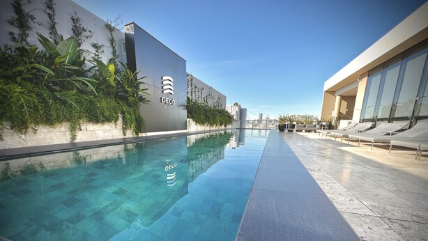 Un espace piscine moderne avec une eau cristalline, entouré d’une terrasse carrelée et de verdure.