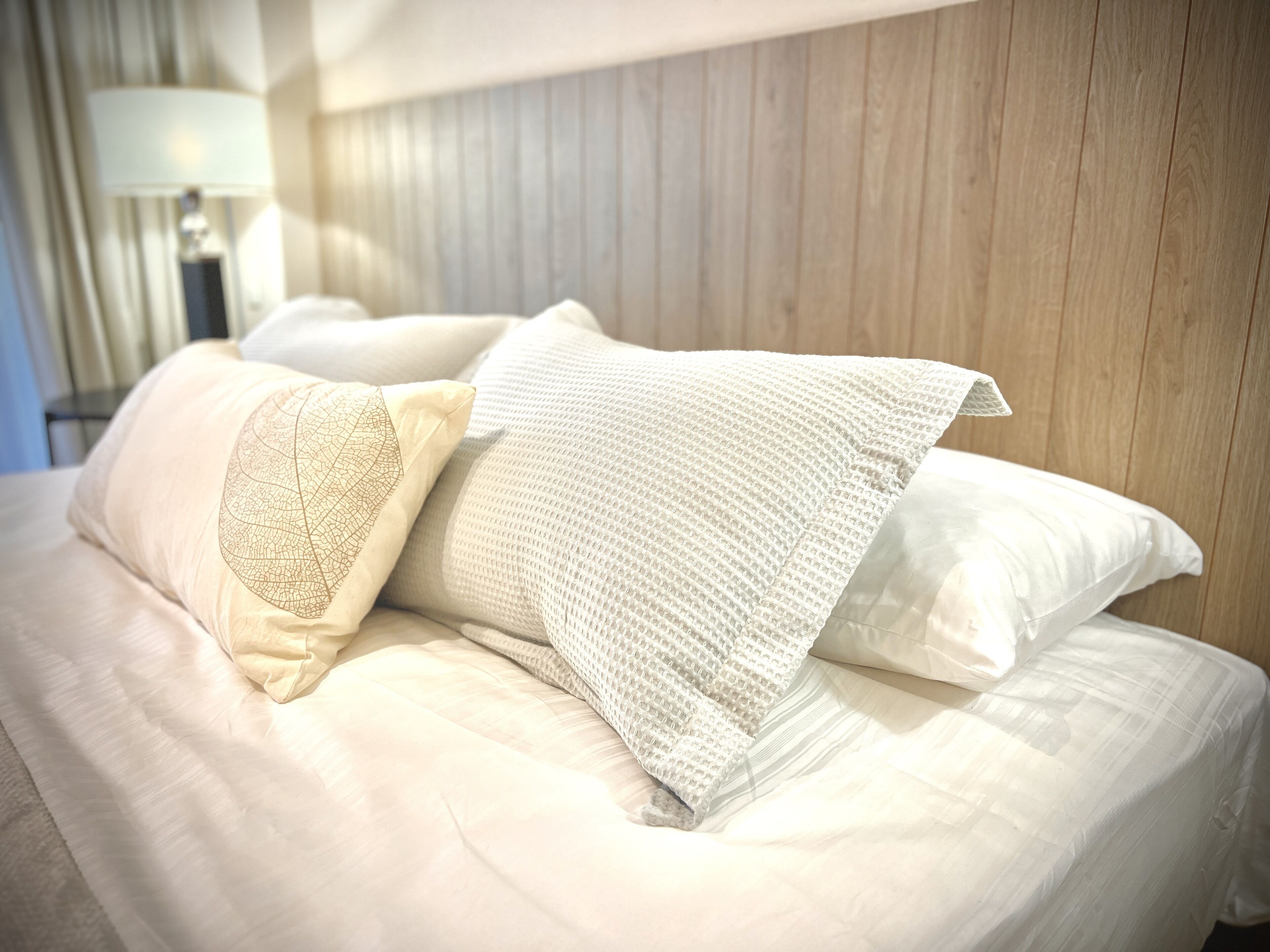 A neatly made bed with white linens and decorative pillows.