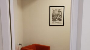 Una habitación con una silla roja, un cuadro en la pared y suelo de madera.