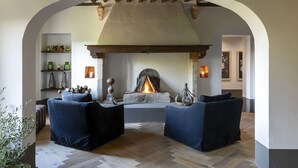 Una sala de estar acogedora con chimenea, dos sofás oscuros y un revestimiento de piedra alrededor de la chimenea.