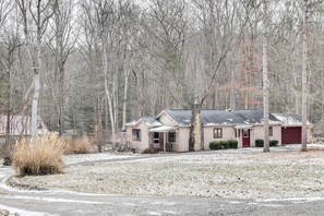 Situated in a wooded area, this cozy home features a front porch with a table and chairs.