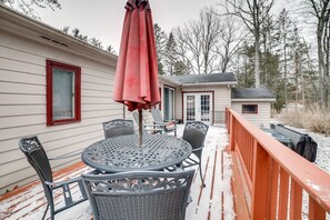 Relax in a cozy outdoor seating area with a round table and four chairs, shaded by a red umbrella.