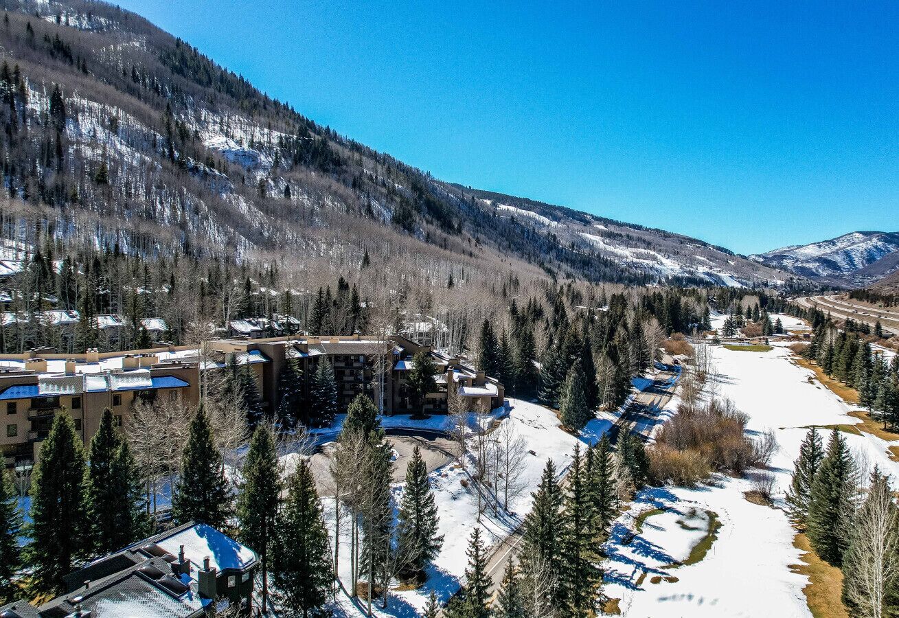 A resort with multiple buildings, a snow-covered landscape, and a mountainous backdrop.