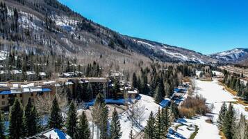 A resort with multiple buildings, a snow-covered landscape, and a mountainous backdrop.