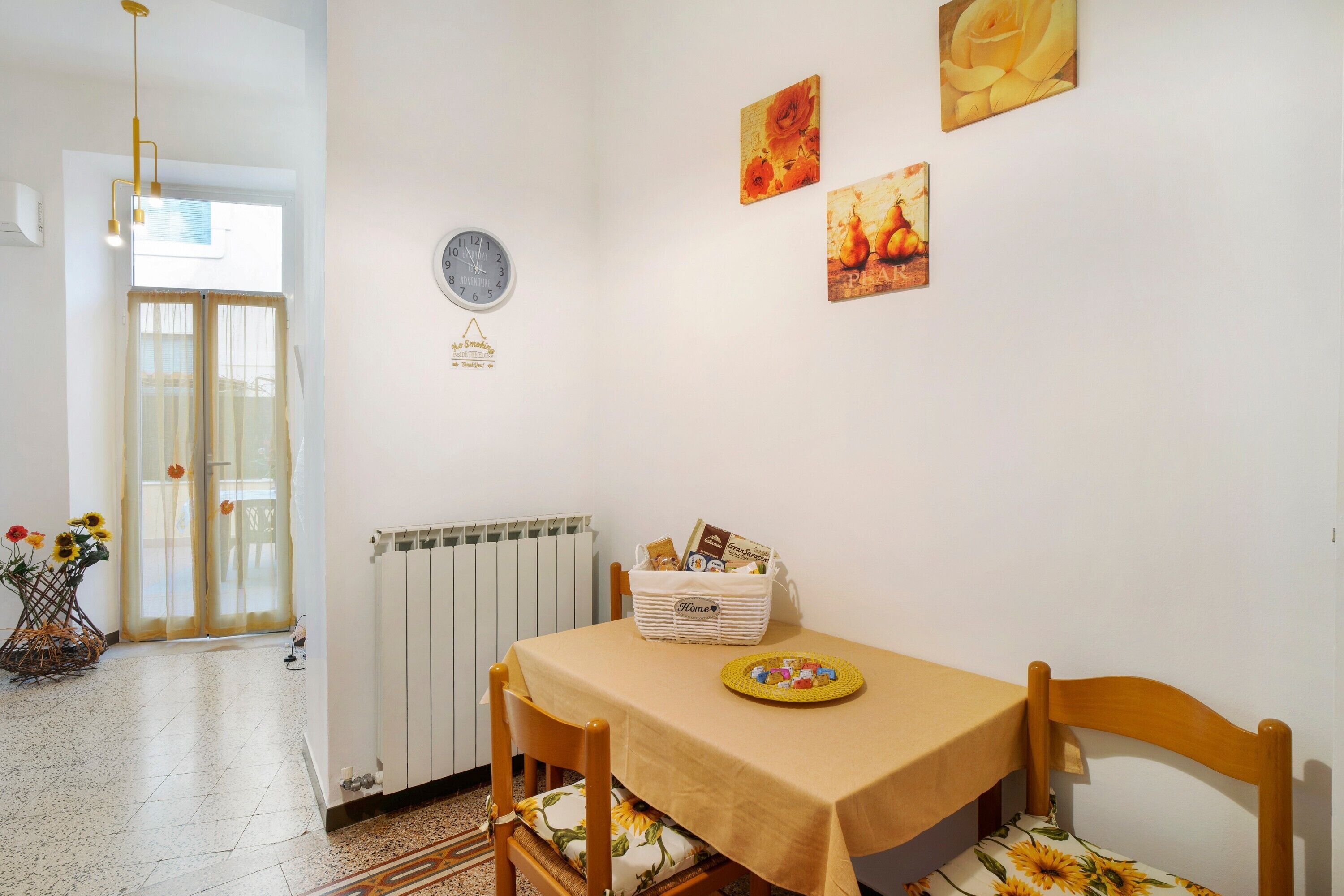 Zona pranzo con tavolo, sedie, orologio e decorazioni a parete.